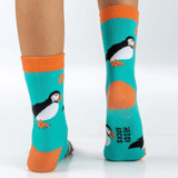 Child wearing turquoise socks, with orange toes and trim and a repeat puffin print
