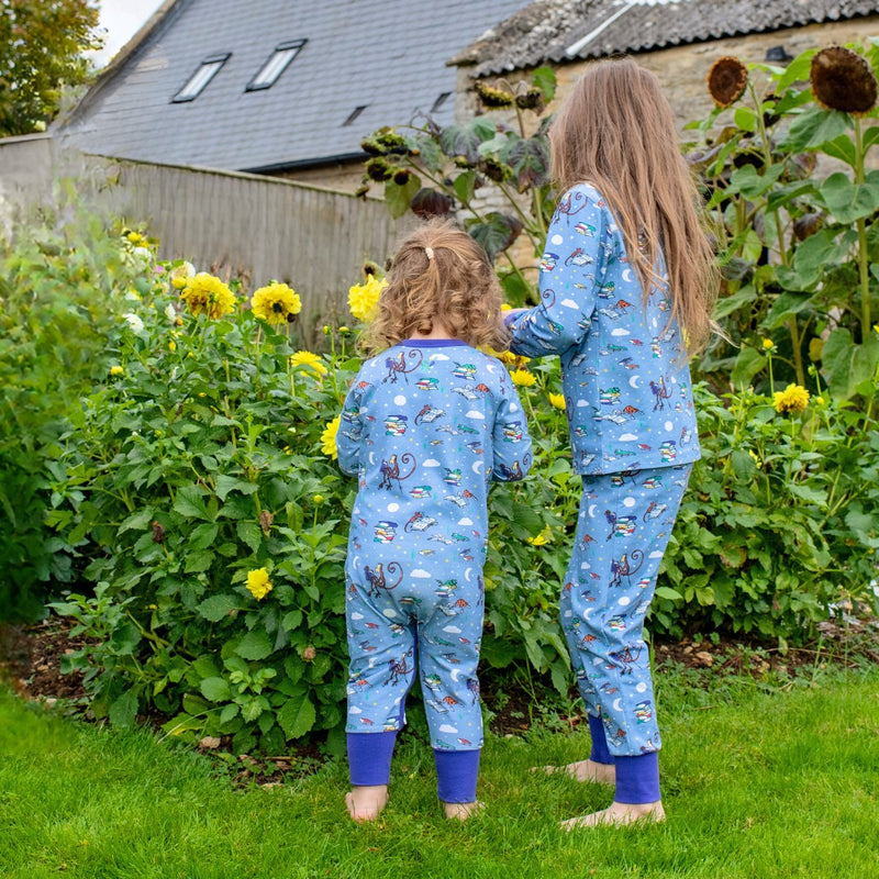 Two children outside looking away from the camera wearing twinning Roald Dahl x Ducky Zebra pyjamas with a fun print promoting story reading.