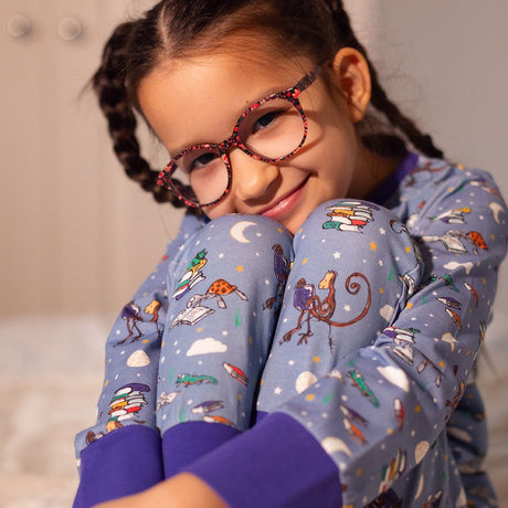 Girl wearing blue Ducky Zebra Pyjamas with Roald Dahl animals reading books and a purple trim