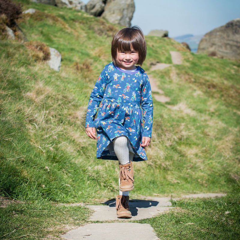 Girl walking across the Yorkshire Moors wearing a playful skater dress with hippos and frogs cycling and walking together
