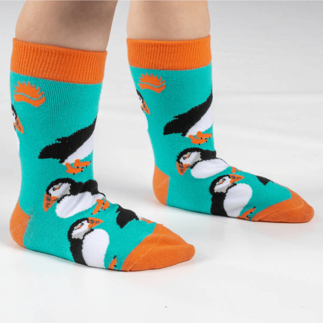 Child wearing fun puffin socks with turquoise background and orange trim