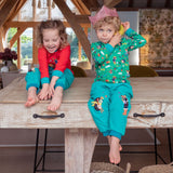 Girl and boy wearing Ducky Zebra turquoise cord trousers with a fun appliqué of a dog and hedgehog throwing leaves at one another. Both children are wearing colourful Ducky Zebra tops, ready for a Christmas party.