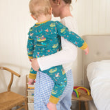 Baby wearing a teal onesie, with a fun highland cow and otter print. The baby is being carried by its mum.
