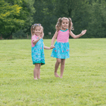 Two children waving at the camera wearing Ducky Zebra 'under the sea' nautical themed dress and dungarees
