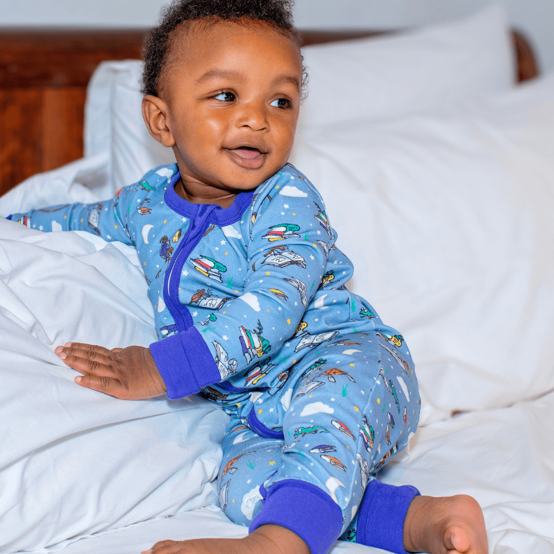 Child wearing blue pajamas with airplane pattern on a bed