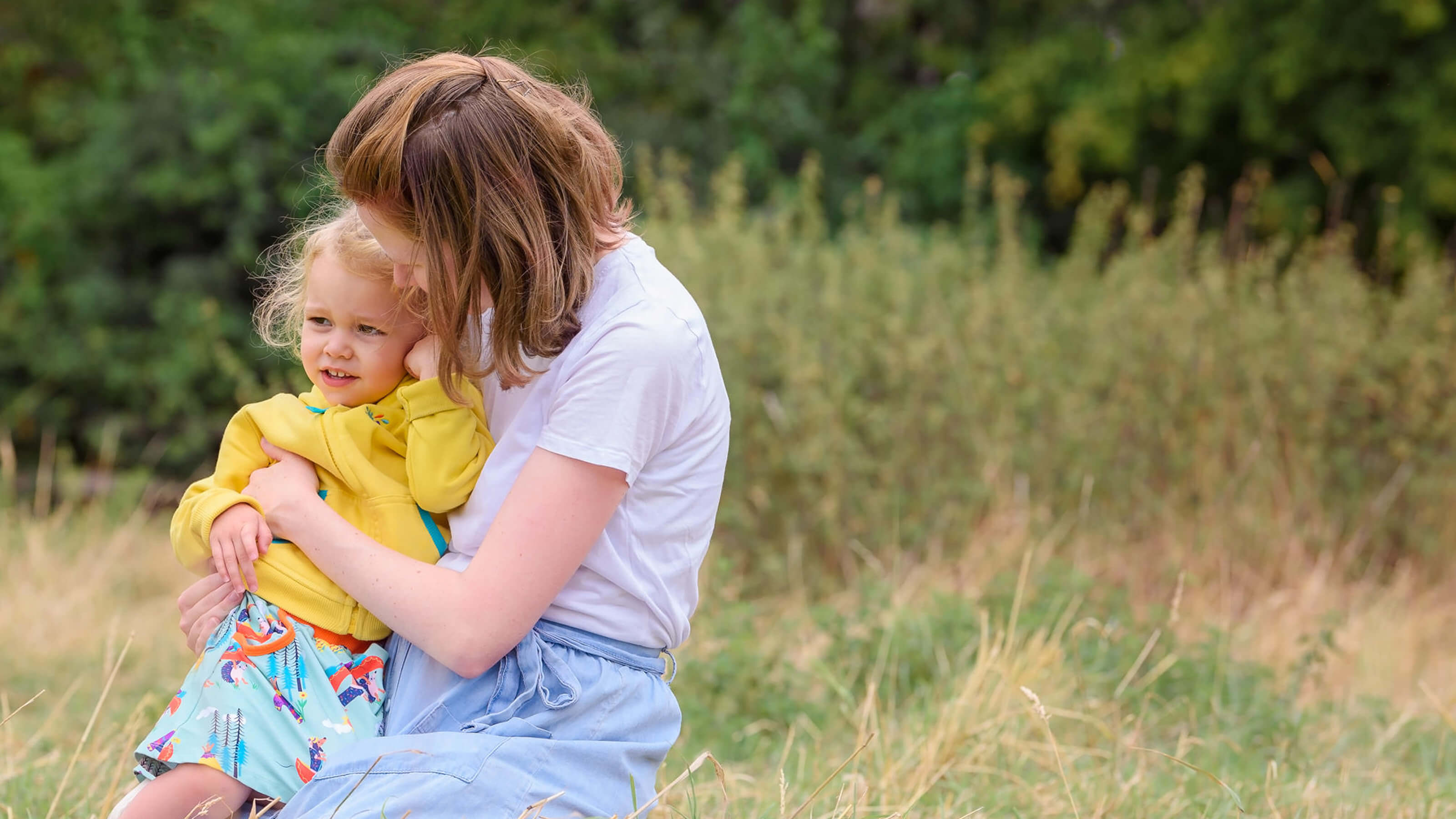 Woman and child sitting together in a grassy field