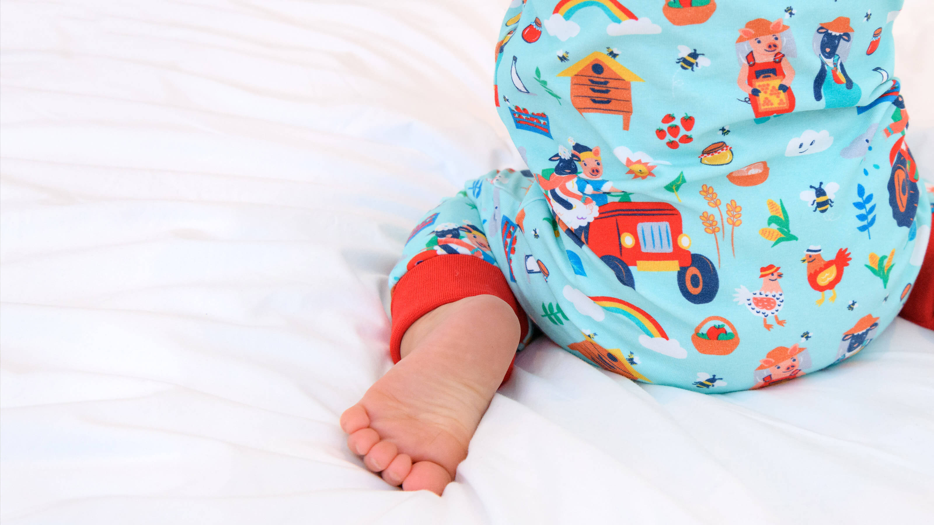 Child wearing a colorful patterned outfit with cartoon characters on a white background