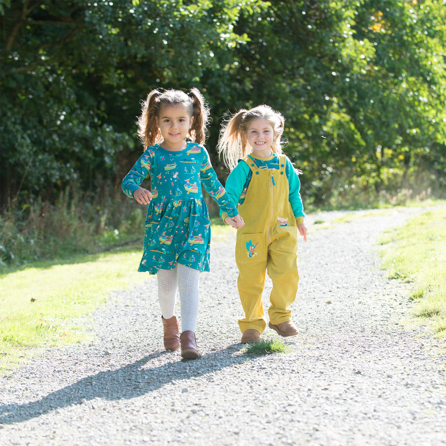 Two young girls walking on a gravel path surrounded by greenery