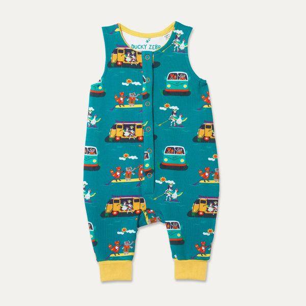 Ducky Zebra teal sleeveless romper with a campervan and paddleboard repeat print. The romper has contrasting yellow cuffs, which have been folded up. It has orange poppers down the front. 