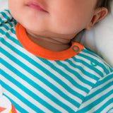 Image of a baby wearing a long sleeve turquoise stripe bodysuit with flame orange trim and roll-up arm cuffs. The image focuses on the neckline of the bodysuit, including two turquoise poppers on the side of the neck for easy opening. 