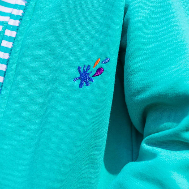 Close up of an embroidered splash motif on a Ducky Zebra turquoise hoodie. The motif is blue, orange and purple