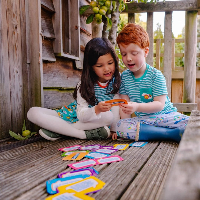 Image of two children sitting in a tree house, wearing Ducky Zebra clothes, playing with the Conversation Cards 
