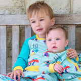Image of a toddler brother and baby sister cuddling together on a bench. They're wearing twinning Ducky Zebra outfits with a repeat print pattern of a dog and hedgehog canoeing