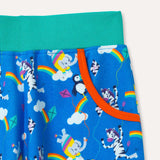 Bright blue joggers with a repeat print pattern of a colourful elephant, zebra and puffin flying kites together. Image is a close up of one of the two pockets with an orange trim and the elasticated turquoise waistband