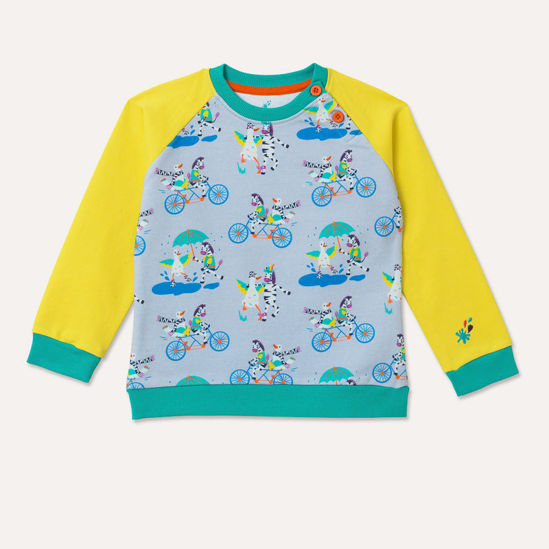 Image of kids raglan sweatshirt with yellow sleeves and repeat print pattern body. The repeat print pattern has images of a duck and zebra splashing in a puddle together, cycling on a bike and running a three legged race