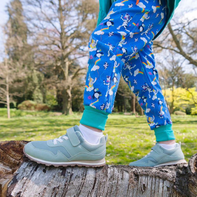 Image of a child balancing on a tree, with a focus on their colourful Ducky Zebra joggers with roll-up leg cuffs 