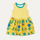 Image of a Ducky Zebra sleeveless dress. The dress has a yellow and white stripe top half with a printed bottom half. The print has a yellow background with a crocodile and elephant enjoying a hot air balloon ride and playing together in the leaves. The dress has two big pockets and two orange buttons on one of the shoulders. 