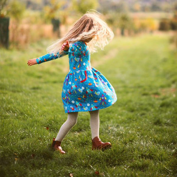 Image of a girl spinning in a long sleeve colourful skater dress with a space print by Ducky Zebra