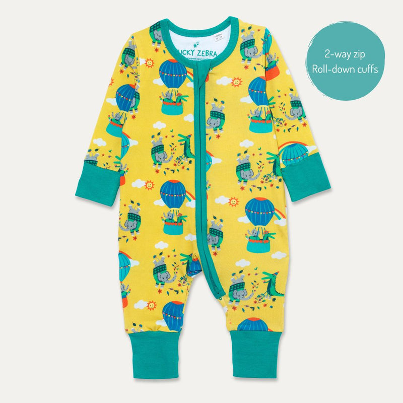 Image of a Ducky Zebra baby sleepsuit. The sleepsuit has a yellow background with a repeat print pattern of a crocodile and elephant enjoying a hot air balloon ride and playing in the leaves. The sleepsuit has a contrasting turquoise two-way zip and roll-down cuffs.