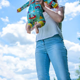 Image of a mum throwing up their baby into the air. The baby is wearing a Ducky Zebra baby romper.