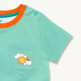 Close up image of a light green Ducky Zebra t-shirt with a contrasting orange trim on the neck. The t-shirt has a front pocket on the right hand side with a fun rainbow print. 