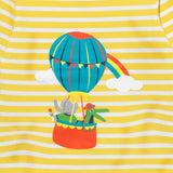 Close up image of a print on a Ducky Zebra yellow and white stripe t-shirt. The print is of a crocodile and elephant enjoying a hot air balloon ride together, with a rainbow in the background. 