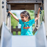 Image of a child at the top of a slide, wearing a turquoise Ducky Zebra t-shirt with a contrasting orange trim and a print of a hedgehog and sausage dog rowing a boat on the front.